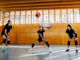Volleyball Training: Spielerinnen trainieren gemeinsam verschiedene Schlagtechniken in der Halle.