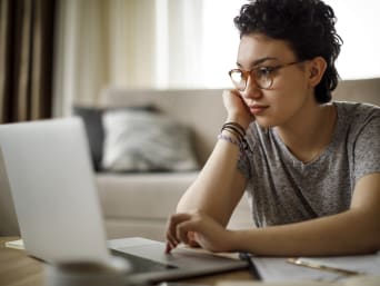 Een studente gebruikt haar laptop om informatie over universitaire vakken te vinden.