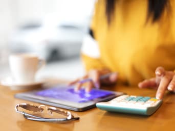 Financování studia: Žena si pomocí kalkulačky vypočítává příjmy a výdaje.