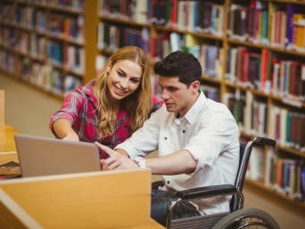Corsi di laurea: uno studente sulla sedia a rotelle studia con una compagna.