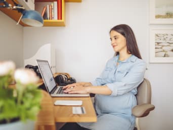 Ciąża a studia: przyszła mama uczy się do egzaminu na laptopie.