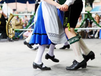 Taniec ludowy z różnych zakątków świata: para w bawarskich strojach ludowych tańczy na Oktoberfest.