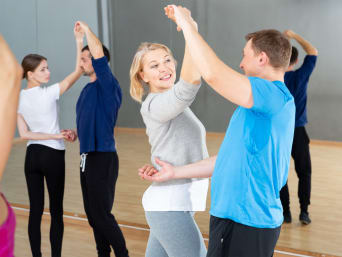 Deelnemers aan een dansles trainen in de dansstudio voor een spiegelwand.