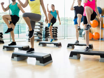 Dance workout: cursisten trainen met step-aerobics in de sportzaal.