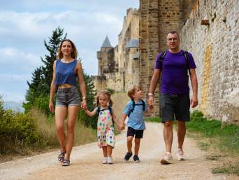 Eine Familie mit Kindern wandert an einer Burgmauer entlang. Eine Familie mit Kindern wandert an einer Burgmauer entlang.
