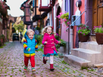 Kinder rennen durch eine Straße mit schönem Fachwerk.