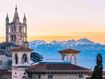 Herzroute: Kathedrale von Lausanne mit Bergen im Hintergrund.