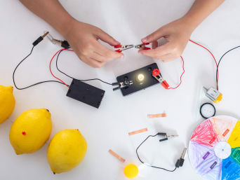 Experimentos con electricidad para niños: un niño construye una pila con un limón.