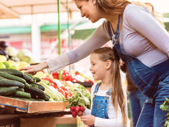 Spesa sostenibile: madre e figlia comprano prodotti di stagione al mercato.