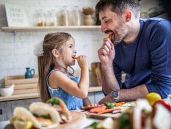 Klimafreundlich essen: Vater und Tochter naschen Rübli beim Kochen.