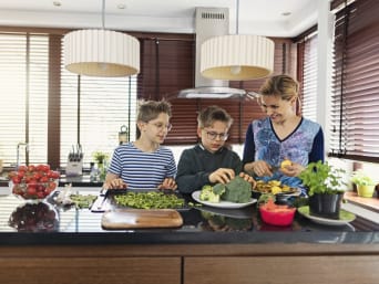 Cibo sostenibile: madre e figlio cucinano insieme con ingredienti freschi e sani. 