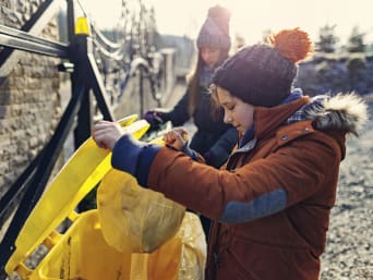 Comment trier ses déchets	 avec ses enfants : un garçon jette une poubelle dans le bac jaune. 