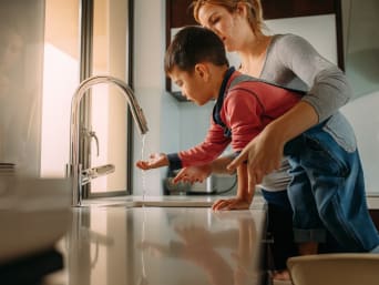Esperimenti con l’acqua e risparmio acqua – Una mamma e un bambino usano un rubinetto.