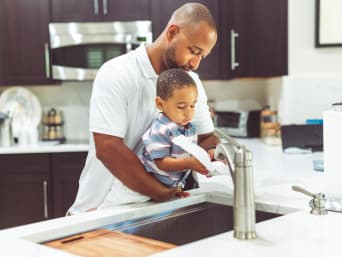 Doświadczenia z wodą dla dzieci: ojciec i syn moczą ręcznik kuchenny.