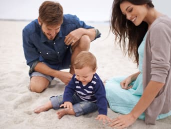 Wakacje z dzieckiem – mały chłopiec bawi się piaskiem na plaży.