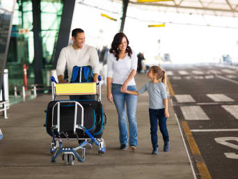 Voyager en avion avec des enfants : des parents avec leur petite fille à l'aéroport.
