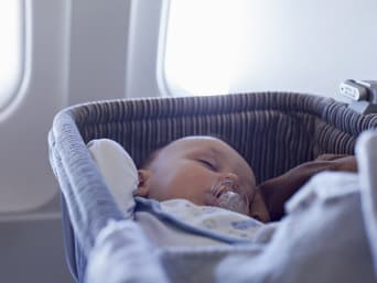 Niemowlę w samolocie: bobas śpi spokojnie w specjalnym łóżeczku samolotowym.