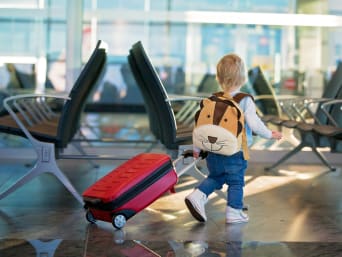 Bagaż podręczny dla dziecka: mały chłopiec z plecakiem i walizką dziecięcą. 
