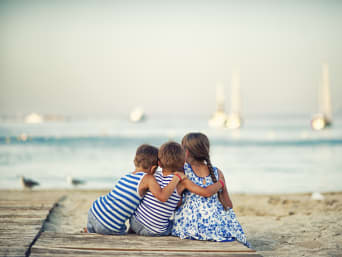 Vacaciones en Mallorca con niños: tres hermanos disfrutan de un día de playa en el Mediterráneo.