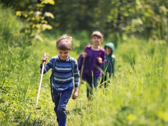 Surselva wandern mit Kindern: Kinder wandern durch eine grüne Wiese.