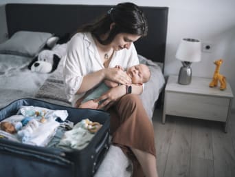 Erste Ferien mit Baby – Mutter packt die Koffer für die ersten Ferien mit Baby.