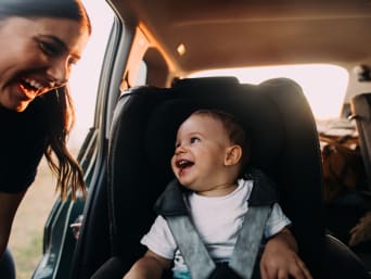Ferienvorbereitungen – Mutter und Vater bereiten ihr Kind auf die Reise im Auto vor.