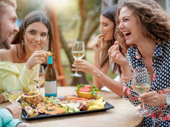 Genussurlaub: Gruppe von Freunden genießt zusammen ein Glas Wein und eine Obstplatte.