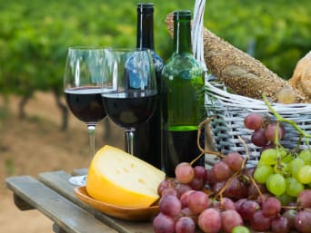 Spezialitäten Mosel: Rotwein, Trauben, Käse und Brot stehen auf einem Tisch zur Verkostung bereit.