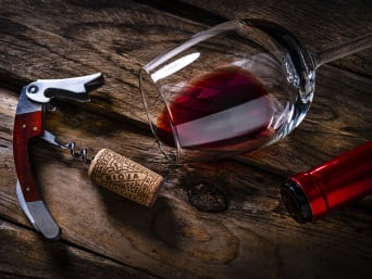 Vinos Rioja: un tapón de corcho, un sacacorchos y una copa de vino encima de una mesa.