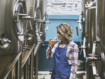 Belgisch speciaalbier: vrouw neemt in een brouwerij een slok van een biertje.