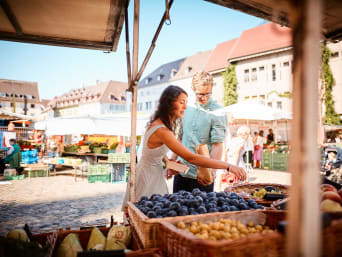 Spezialitäten Vorarlberg: Paar kauft Obst an einem Stand auf dem Markt.