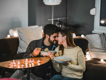 Cosa fare a San Valentino: una coppia mangia insieme a casa a lume di candela.