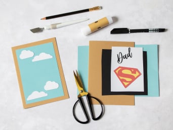 Materialen voor een vaderdagkaart met superheldenlogo.