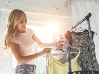 What are delicates?: a woman sorting through various clothes on a clothes rack. 