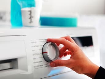 Lavaggio in lavatrice: una donna imposta il programma lavatrice adatto al tipo di capo da lavare.