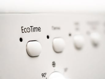 Programmi lavatrice: donna seleziona il programma a risparmio energetico.