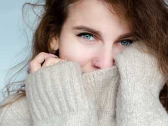 La femme porte un pull en cachemire rayé.
