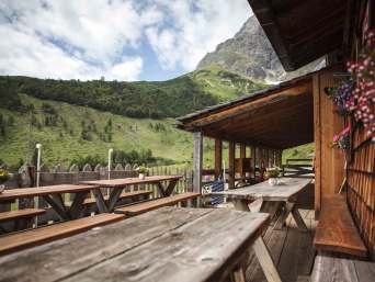 Hüttenwanderung für Anfänger: Tische auf einer Almhütte.
