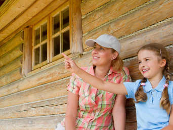 Hüttenwanderung Kinder – Mutter und Tochter sitzen vor einer Hütte. 