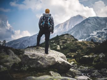 Trekking – samotny wędrowiec rozkoszuje się widokiem górskiej panoramy.