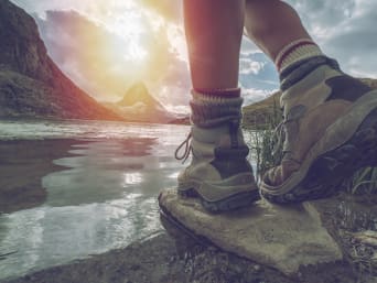 Podróżnik w górach nad jeziorem w odpowiednich butach i skarpetach trekkingowych.
