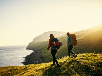 Due escursionisti con zaino e attrezzatura da trekking si avvicinano alla costa.