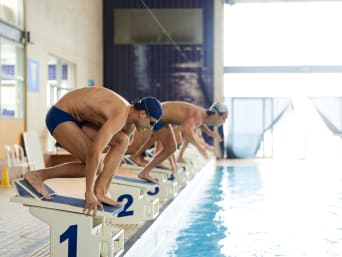 Staffelschwimmen: Schwimmer warten auf ihrem Staffelblock darauf ins Wasser zu springen.