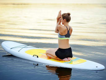 SUP-Board – Vrouw beoefent SUP yoga op rustig water.