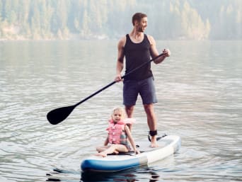 SUP-kinderen – Klein meisje vaart met een zwemvest mee op een gezinsboard