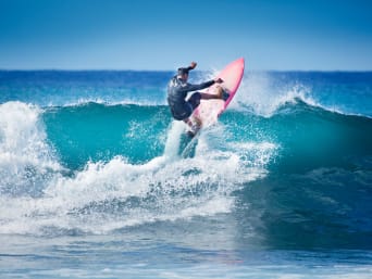Surfen: Surfer startet mit seinem Surfboard auf eine Welle.