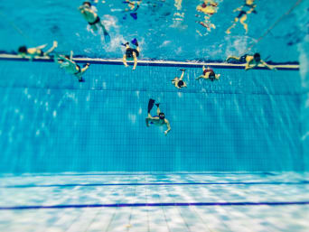Unterwasserhockey Training: Einige Taucher mit Flossen trainieren in einem tiefen Schwimmbecken.