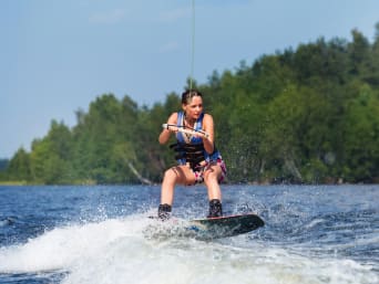 Wakeboard – Frau nutzt eine Wakeboard-Anlage auf einem See.
