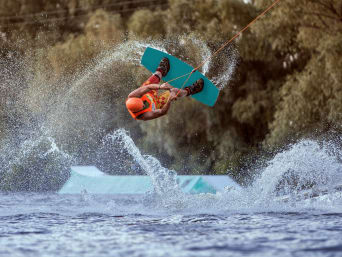 Équipement wakeboard : un wakeboarder fait un saut à l’aide d’un tremplin