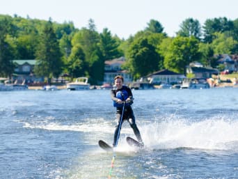 Wasserskien – Waterskiester in wetsuit wordt door een speedboot getrokken.